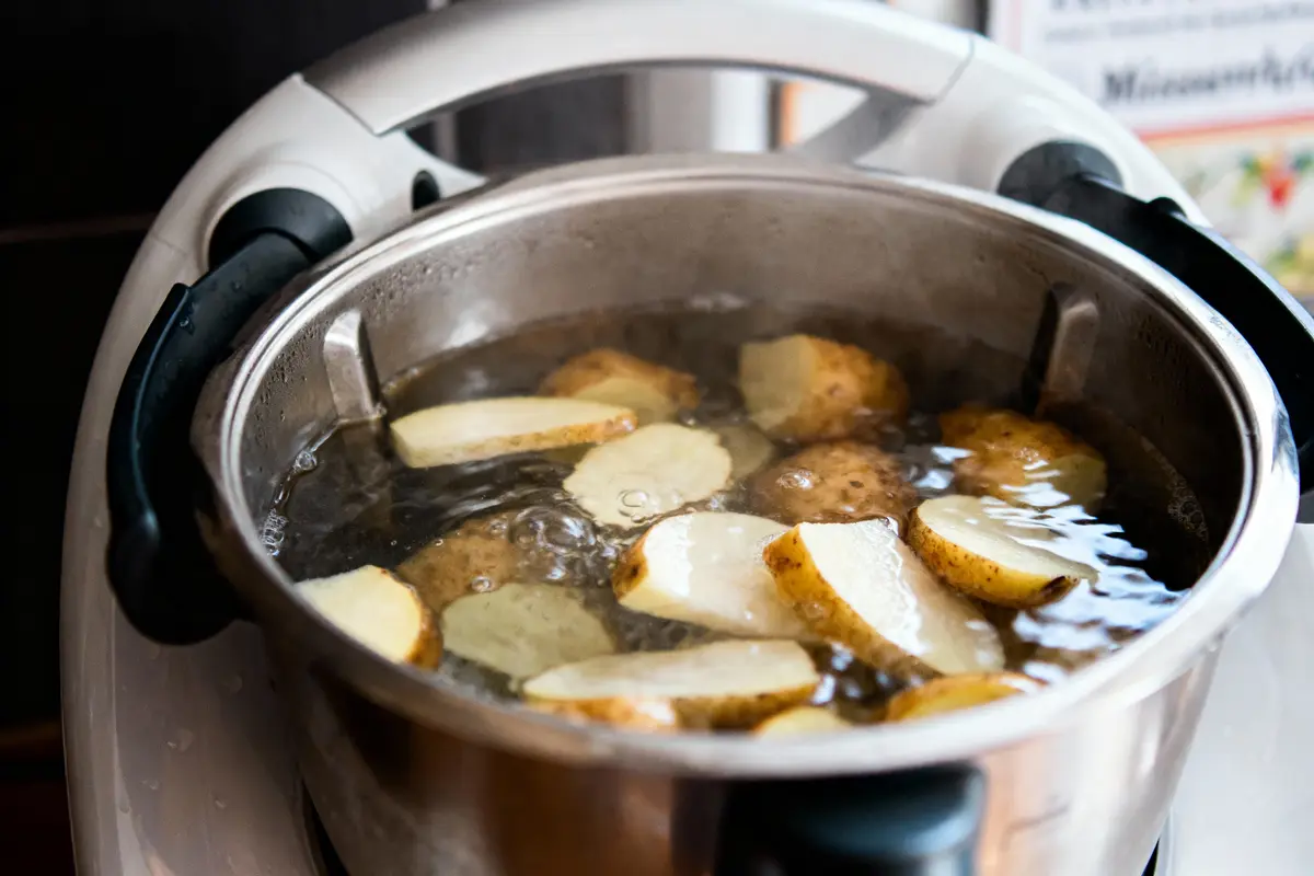 Pommes de terre en tranches bouillant dans une casserole en métal sur une cuisinière électrique.