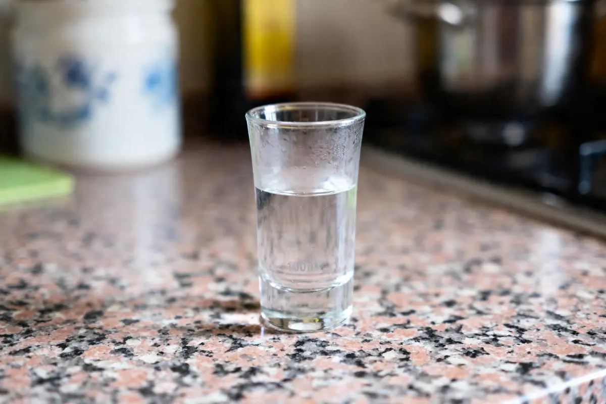 Un verre d'eau posé sur un plan de travail en marbre dans une cuisine.