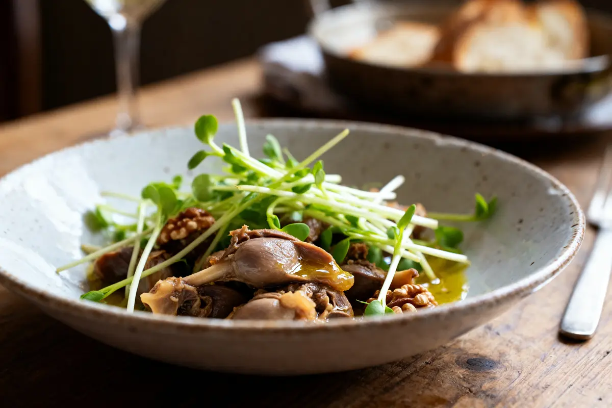 Salade de gésiers avec noix et jeunes pousses servie dans une assiette rustique